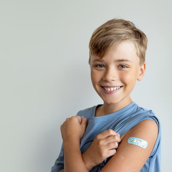 fröhlicher Junge mit Pflaster auf Oberarm